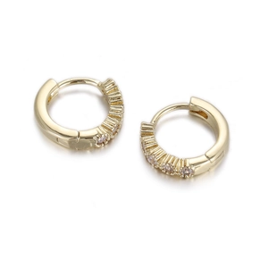 Detailed close-up of golden huggie earrings with sparkling inlaid cubic zirconia crystals