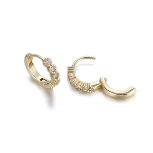 Detail of gold huggie earrings with five inset cubic zirconia and hinge mechanism