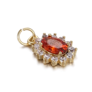 Detail eines vergoldeten Anhängers mit ovalem orangem Edelstein und weißen Zirkonia