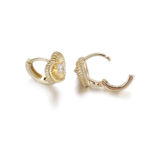 Detailed close-up of golden heart-shaped huggie earrings with central zircon and radiating texture