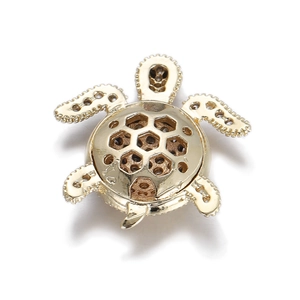 Macro detail of golden turtle pendant with honeycomb cutout shell and textured edges