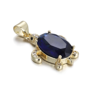 Detailed close-up of a golden sea turtle pendant featuring a large blue faceted gemstone
