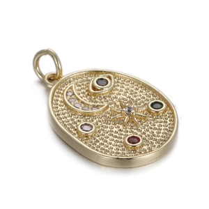 Detail van ovale gouden hanger met maan- en stermotieven en kleurrijke zirkoon