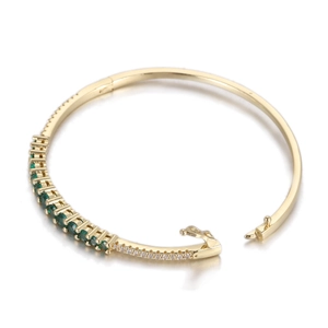 Détail d'un bracelet doré avec oxydes de zirconium verts et pierres pavées brillantes