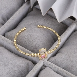 Détail du bracelet à billes dorées avec un ours pavé et une pierre en forme de cœur rose