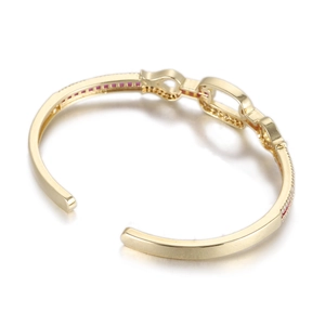 Détail d'un bracelet en C plaqué or 14 carats avec incrustations de zircons rouges et blancs