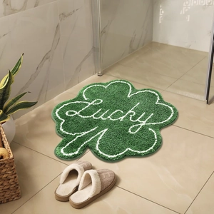 Detail of green clover bathroom mat with Lucky script on plush faux cashmere rug
