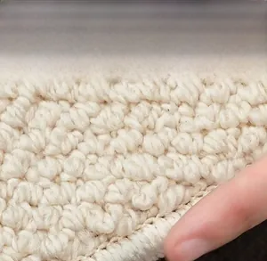 Detail of machine-woven embroidery edge on a durable sisal-style cream area rug