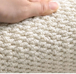 Close-up of hand pressing on cream-colored sisal-style loop pile rug texture