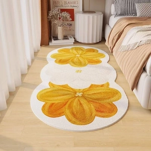 Detail of soft irregular bedside rug with yellow floral patterns on light wood floor
