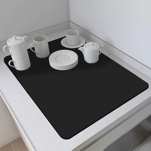 Detalle del tapete de secado negro con juego de té de cerámica blanca sobre mármol