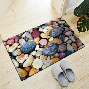 Rectangle 3D pebble footprint doormat shown on light wood floor with slippers