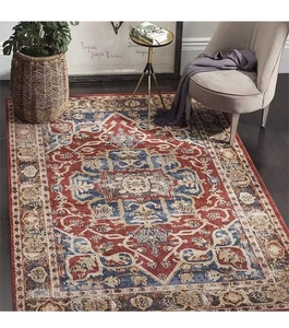 Detail of bohemian Persian rug with intricate brick red and navy patterns on dark wood floor