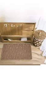 Detail of tan pebble textured absorbent memory foam bath mat on light wood floor