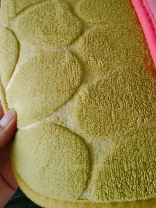 Detail of green pebble pattern coral fleece rug with soft texture and pink border edges