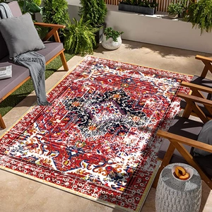 Outdoor Persian rug with red ethnic geometric patterns on a sunny terrace with furniture