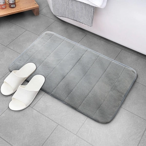 Absorbent grey striped coral fleece bathroom mat on tile floor near bathtub