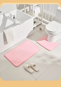 Detail of pink cobblestone embossed bath mat set beside bathtub and toilet in bathroom