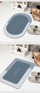 Detail of gray oval absorbent bath mat with HOME text and non-slip rubber backing