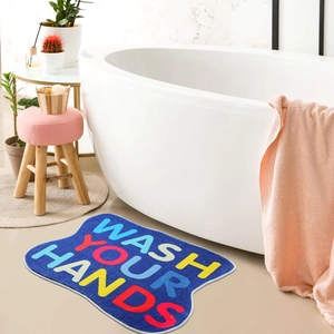 Detail of blue faux cashmere bath mat with Wash Your Hands slogan by a white bathtub