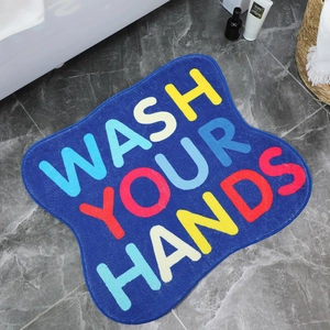 Detail of soft plush navy bathroom mat with colorful WASH YOUR HANDS lettering on marble floor