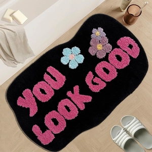 Irregular faux cashmere bath mat with 'You Look Good' text and floral pattern on wood floor