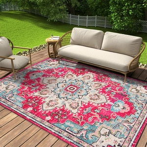 Tapis d'extérieur bohème rose avec motif persan posé sur une terrasse en bois