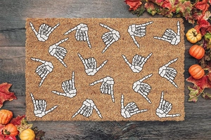 Close-up of rectangular Halloween doormat with white skeleton hands on wooden floor