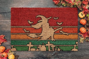Detail of Halloween doormat with witch and bat silhouette over autumn pumpkin decor
