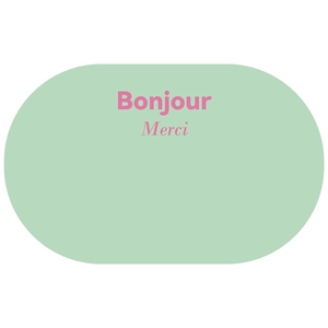 Detail showing an oval mint green absorbent bath mat with pink Bonjour and Merci text