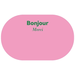 Close-up of minimalist pink bath mat featuring green Bonjour and Merci text detail