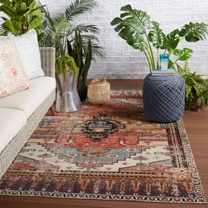 Bohemian style area rug with geometric medallion pattern on dark wood floor for living room