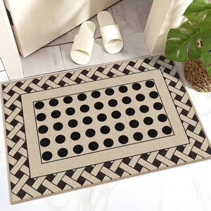 Close-up of luxury beige entryway mat with black polka dots and geometric woven border