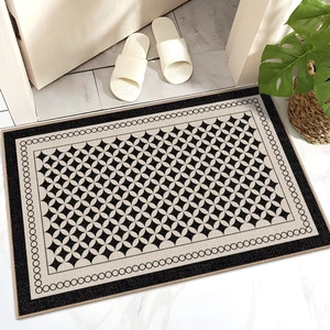 Detailed view of beige and black starburst pattern door mat with non-slip edge