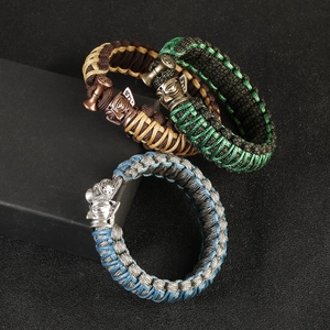 Detailed close-up of woven paracord bracelets with engraved metal mask buckles