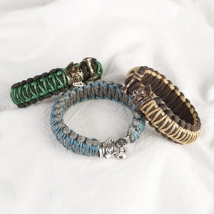 Handmade woven paracord bracelets with star and mask charms in green, blue and brown tones