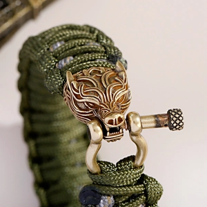 Makroaufnahme von olivgrünem Paracord-Armband mit bronzenem Wolfskopf-Schäkelverschluss