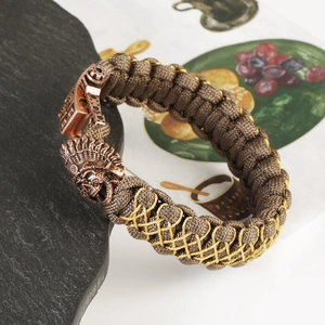 Macro detail of brown paracord bracelet with antique copper tribal chief metal clasp