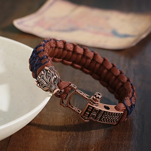 Macro shot of a Viking-style braided bracelet featuring a detailed bronze wolf head charm