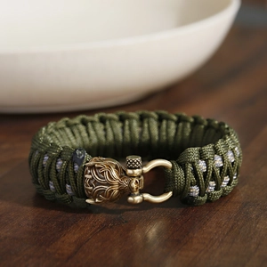 Nahaufnahme von grünem Paracord-Armband mit Drachenkopf-Metallverschluss und Schraubbolzen