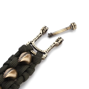 Detail eines olivgrünen Paracord-Armbands mit Messing-U-Verschluss und zirkonia-besetzten Perlen