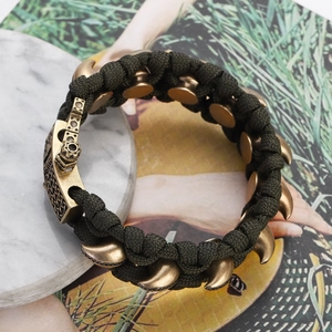 Detail eines armee-grünen Paracord-Armbands mit bronzefarbenen Krallenanhängern