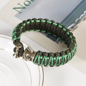 Detail of woven army green paracord bracelet with bronze viking helmet metal buckle