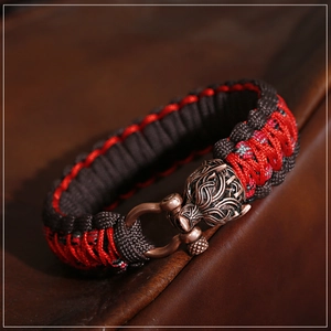 Makrodetail der Wikinger-Drachenkopfschnalle am roten und braunen Paracord-Armband