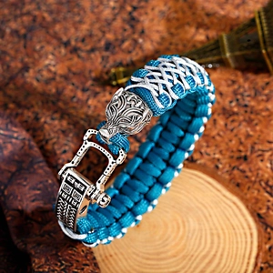 Close-up of paracord bracelet with silver wolf head charm and vintage U-shackle clasp