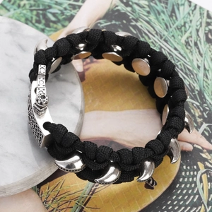 Nahaufnahme von schwarzem geflochtenem Paracord-Armband mit silbernen Krallenanhängern