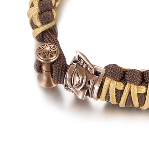 Macro shot of hand-woven tactical paracord bracelet with bronze tribal deity charm