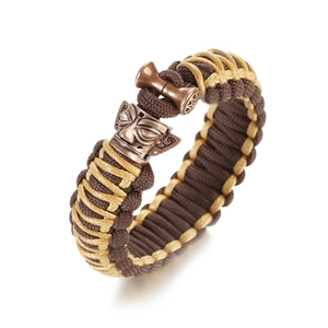 Detailed macro of the dual-color woven cord bracelet with an antique bronze mask buckle