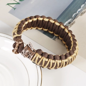 Detail of hand-woven paracord bracelet with antique bronze Sanxingdui mask metal charm