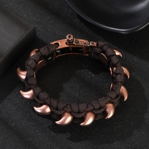 Detailaufnahme des braunen Paracord-Armbands mit bronzenen Klauen-Anhängern und mechanischem Verschluss
